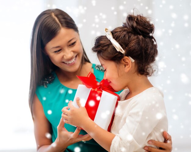 christmas, holidays, family and people concept - happy mother and child girl with gift box at home