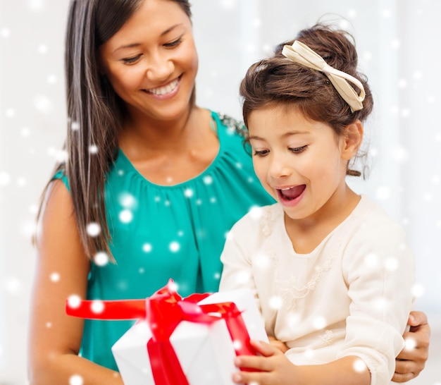 christmas, holidays, family and people concept - happy mother and child girl with gift box at home