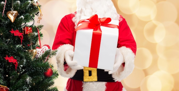 크리스마스, 휴일 및 사람 개념 - 베이지색 조명 배경 위에 선물 상자와 나무가 있는 산타클로스 클로즈업