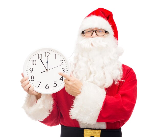 christmas, holidays and people concept - man in costume of santa claus with clock showing twelve pointing finger