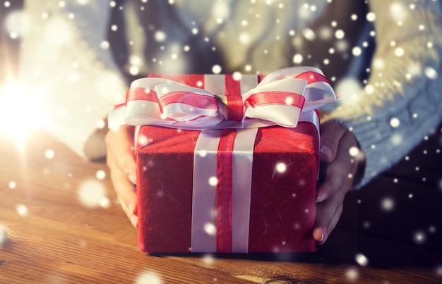 Рождество, праздники, подарки, Новый год и концепция людей - крупный план женских рук, держащих подарочную коробку, украшенную луком