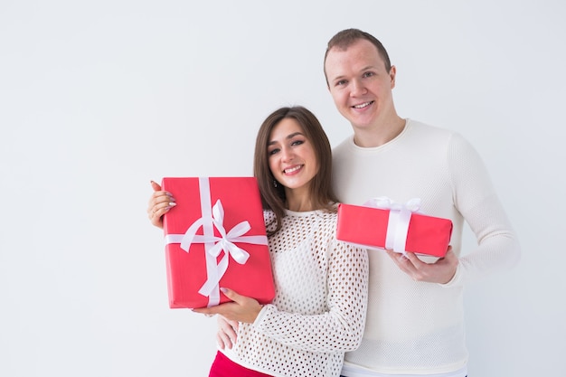 Natale, vacanze, san valentino e concetto di compleanno - l'uomo e la donna felici tengono scatole con regali su sfondo bianco