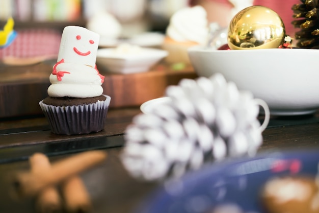 Рождественский самодельный кекс украшают, как снеговик на столе.