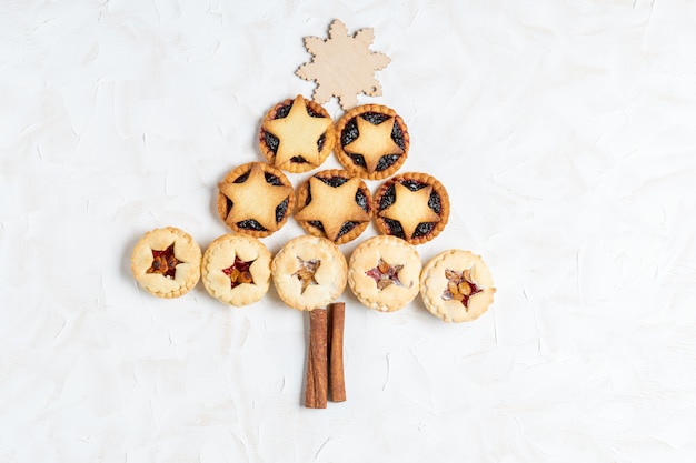 Christmas homemade mince pies in form of Christmas tree on white cement background