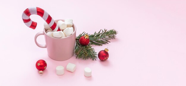 Christmas hot beverage chocolate mug marshmallows and xmas\
decoration on pastel pink background