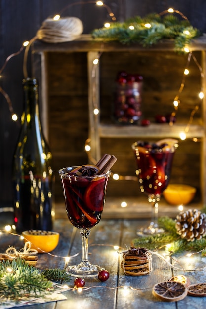 Christmas hot mulled wine in a glass with spices, citrus fruit and cranberry. Christmas atmosphere.