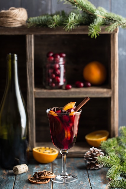 Christmas hot mulled wine in a glass with spices, citrus fruit and cranberry. Christmas atmosphere.