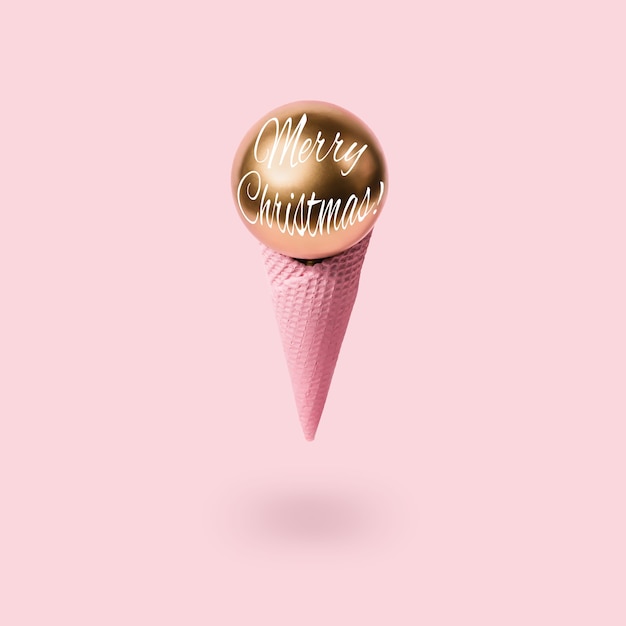 Christmas ice cream cone and golden ball levitate. Trendy holiday concept.