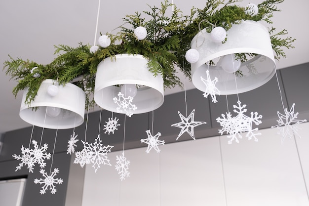 Christmas interior decoration white knitted snowflakes fir branches and christmas lights on a chande...