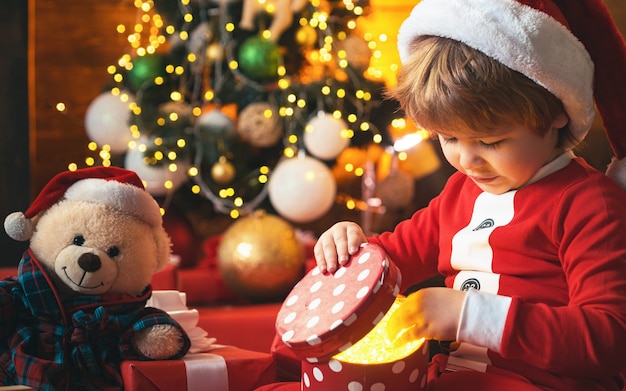 クリスマスの子供。クリスマスのギフトボックスと幸せな小さな笑顔の少年。赤いギフトボックスを持って幸せな子