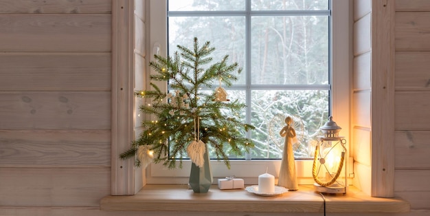 Christmas lantern christmas angel christmas tree and white decor on the window of a wooden house