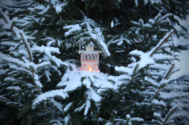 Photo christmas lantern with burning candle on winter nature background.