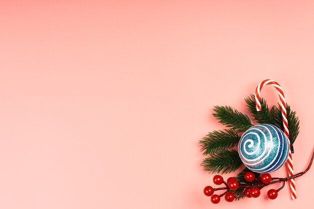 Christmas layout blue glitter Christmas balls with spruce branches on a pink background. Place for text, flat style, top view. Minimalistic Scandinavian style.