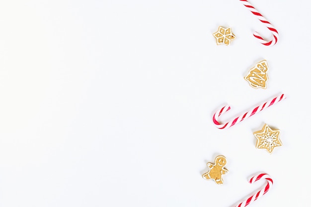 Christmas layout. Striped red-white cane candies and homemade ginger cookies on a white background