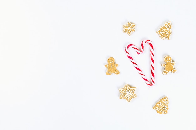 Christmas layout. Striped red-white cane candies and homemade ginger cookies on a white background. 