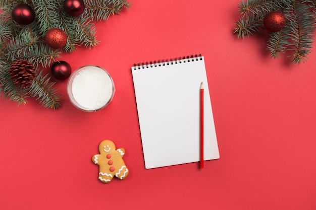 Christmas letter for Santa Claus with milk, cookies, gingerbread on red. Top view and space for your text. Flat lay.