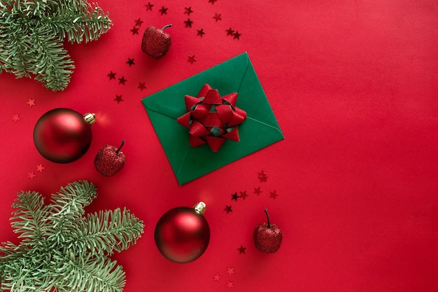 Lettera di natale con biglietto di auguri e congratulazioni, rami di albero di natale, palline, decorazioni glitterate su superficie rossa. buon natale felice anno nuovo concetto.