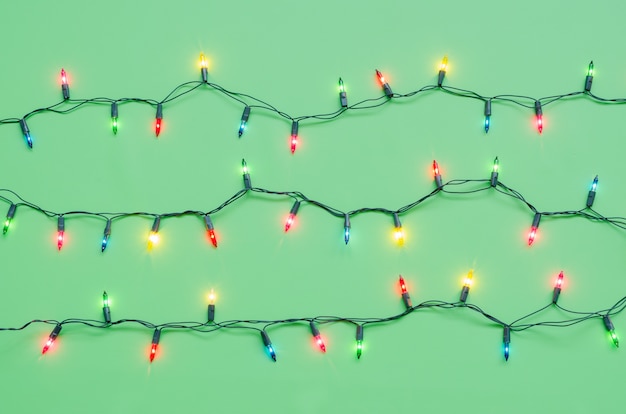 Christmas light bulbs on pattern strings in multi colours on green background for Christmas