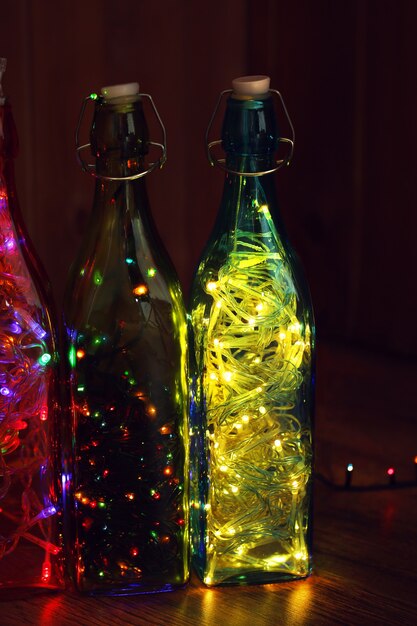 Christmas lights in bottles on wooden surface