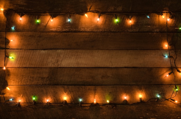 Christmas lights bulb decoration on old wood plank, frame border design. Merry Christmas and New Year holiday background. vintage color tone.