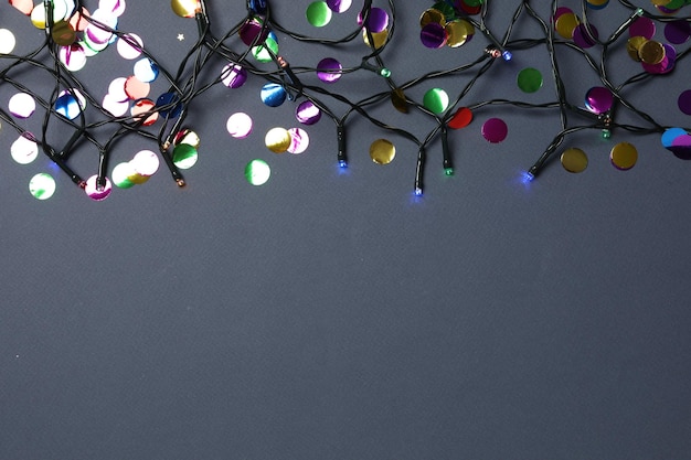 Christmas lights and confetti on dark blue background space for text