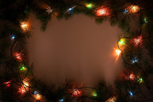 Christmas lights frame on dark background. Holiday shiny garland border top view. Xmas tree decorations, winter holidays illumination