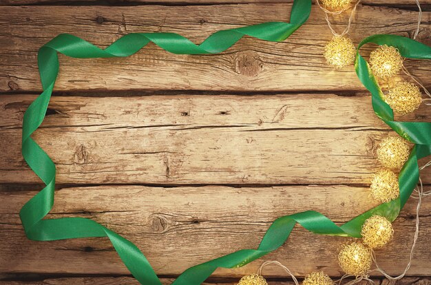 Christmas lights and green ribbon on a wooden background with copy space