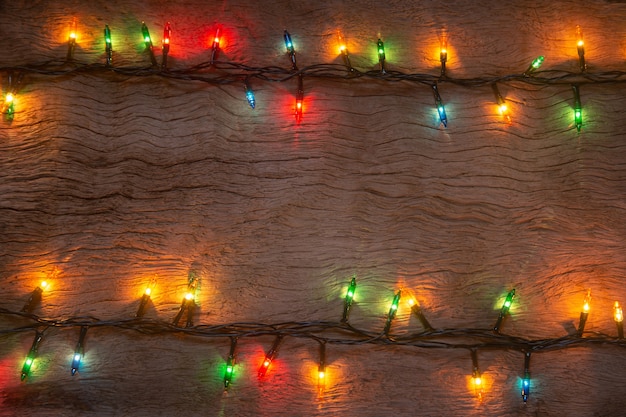 写真 木の板の背景にクリスマスライト。メリークリスマスと新年あけましておめでとうございます。テキスト用のコピースペースがあります。
