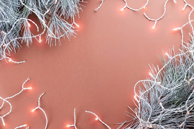 Christmas lights and silver fir branches on brown background, copy space