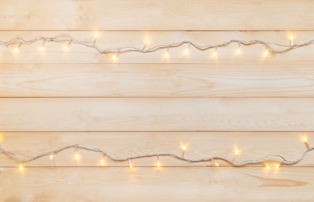 Christmas lights in warm yellow white on string over light wooden background 