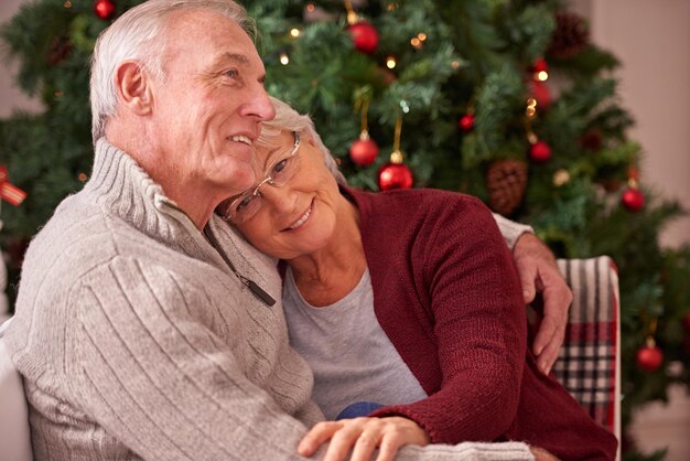 Christmas love and senior couple hug on sofa in home affection and bonding Romance xmas holiday and happy elderly retired woman and man embrace on couch enjoying quality time together in house