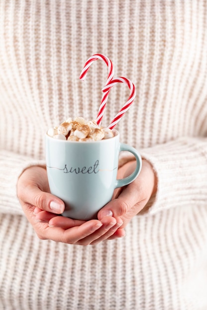 Photo christmas magic scene, cozy atmosphere. 
woman holding cup of drink with marshmallows.
