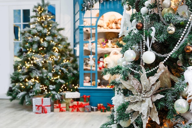 クリスマスの魔法の雰囲気の背景。冬の休日のためのモダンなインテリアデザイン。輝く光で飾られた松の木、おもちゃやプレゼントボックスのショーケース