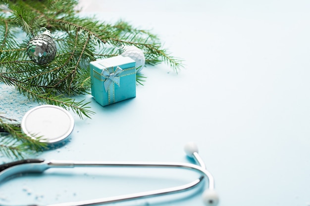 Christmas medical concept with stethoscope gift box and christmas tree on blue