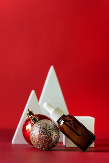 사진 빨간색 배경에 갈색 유리 세럼 병이 있는 크리스마스 미니멀리즘 구성