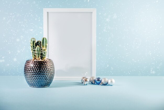 Christmas minimalistic mockup with white frame cactus and christmas balls on blue background