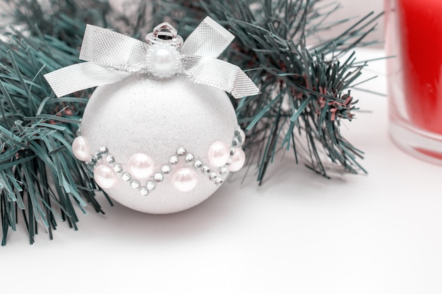Atmosfera natalizia - un ramo di abete, una palla di natale decorativa lucida e una candela rossa