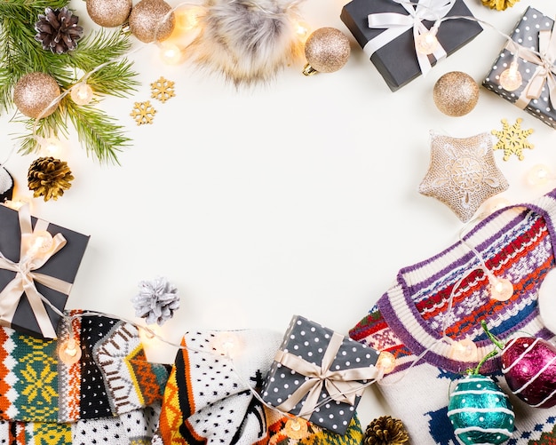 Christmas mood composition with Christmas sweater, hat, presents and lights. Winter concept flat lay, top view