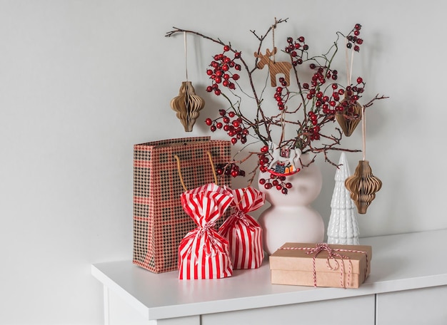 Photo christmas mood gifts cranberry branches in a vase with paper toys on the dresser