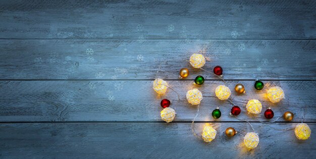 Рождественское настроение Новогодний фон Горящая гирлянда и елочные шары на деревянном фоне с копировальным пространством