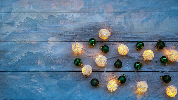 Christmas mood New Year background Burning garland and Christmas balls on a wooden background with copy space