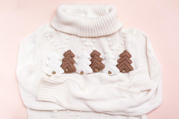 Photo christmas mood. white sweater hugs knitted fir-trees. handicraft decor. zero waste