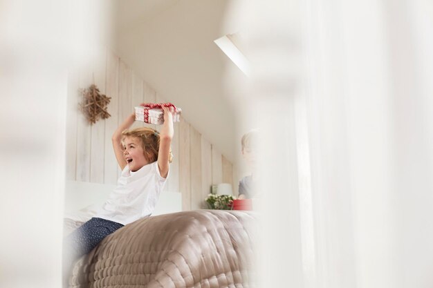 Christmas morning in a family home A girl holding a present above her head