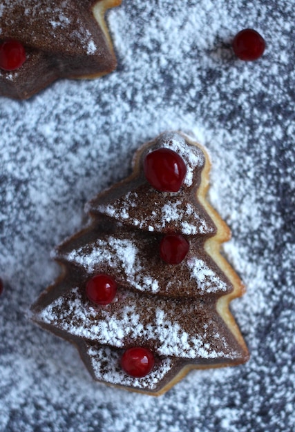 暗い背景にベリー粉砂糖とモミの木の形のクリスマスマフィン