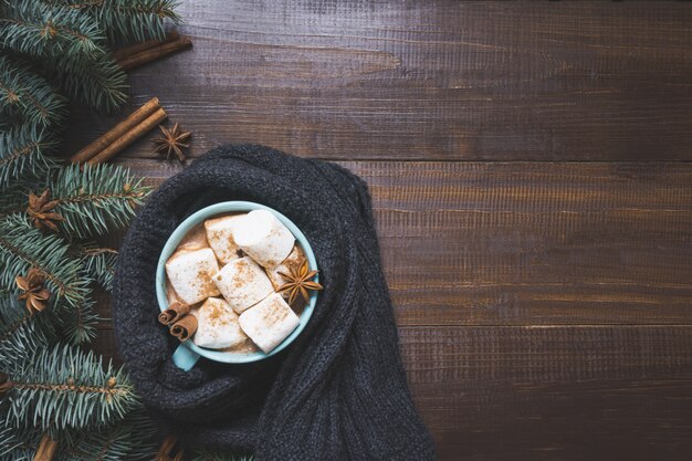 Christmas mug of coffee with marshmallow on dark wooden board. 