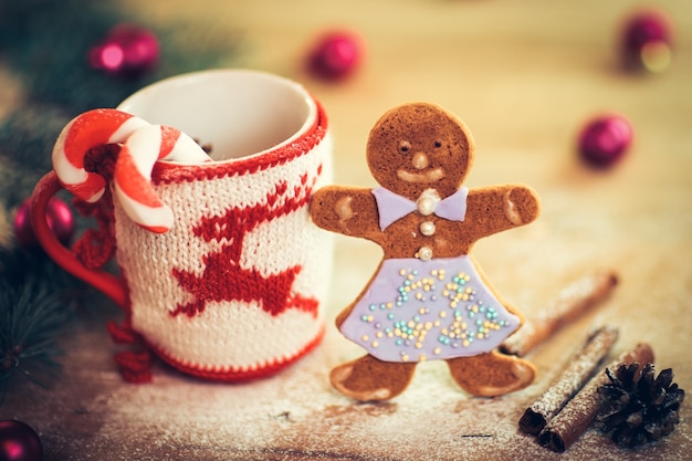 Christmas mug with Christmas decorations and cookies in the shapeman on a wooden background