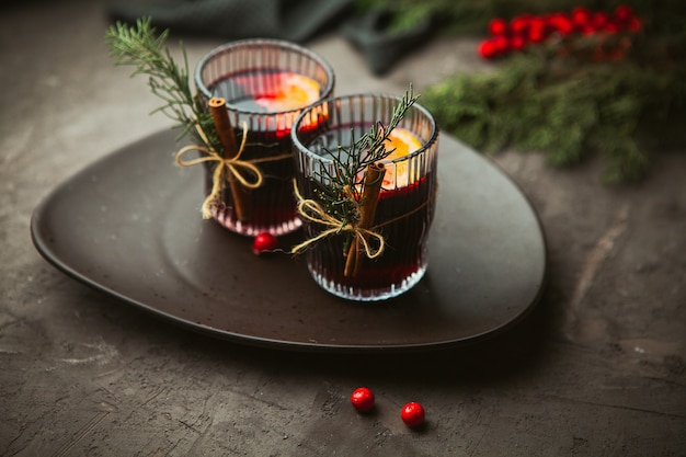 Christmas mulled red wine with aromatic spices and citrus fruits on a plate, close-up. Traditional hot drink at Christmas time