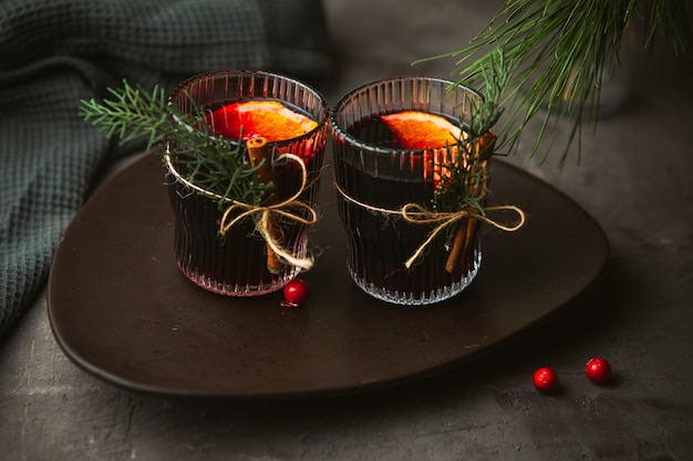 Christmas mulled red wine with aromatic spices and citrus fruits on a plate, close-up. Traditional hot drink at Christmas time