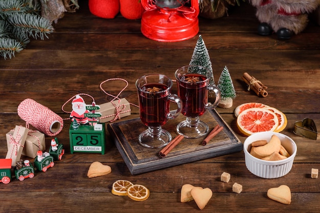 Christmas mulled red wine with spices and fruits on a dark table. Traditional hot drink at Christmas time