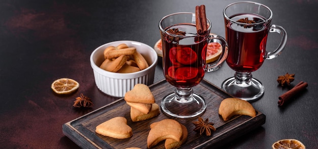 Christmas mulled red wine with spices and fruits on a dark table.